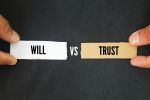Papers with the words trust vs will. Visual concept for estate planning blog that discusses the difference between a will and a trust.